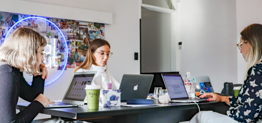 Women sitting around a shared desk planning a paid search strategy